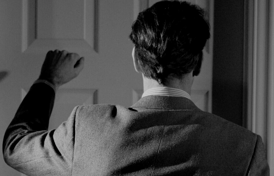 

The silhouette of a hacker in a hood, working at a computer, against the background of code and dollar symbols.

