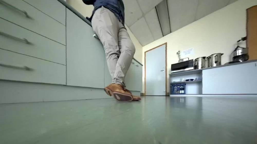 The robot continues its journey through the unfamiliar kitchen, capturing legs in the frame.