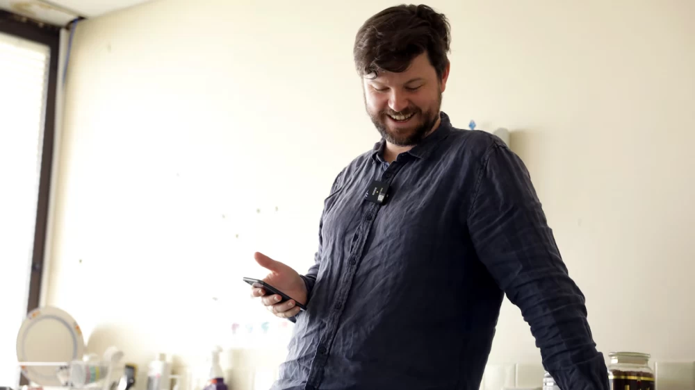 Sean Kelly laughs in surprise as his robot says it is watching him