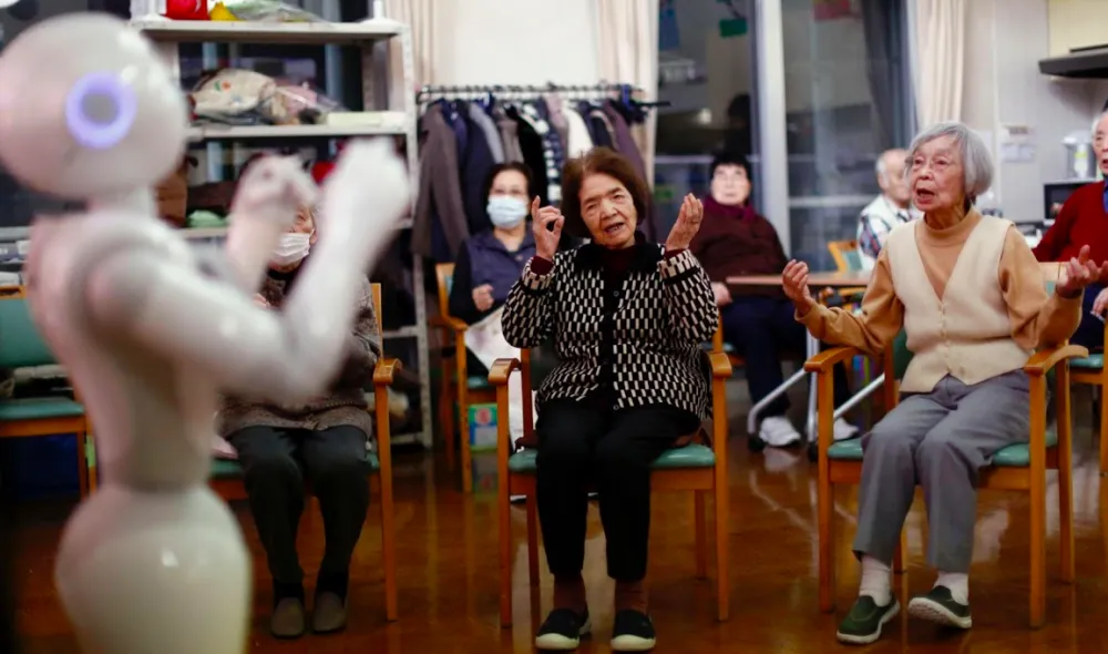 The robotic assistant serves water to an elderly person.
